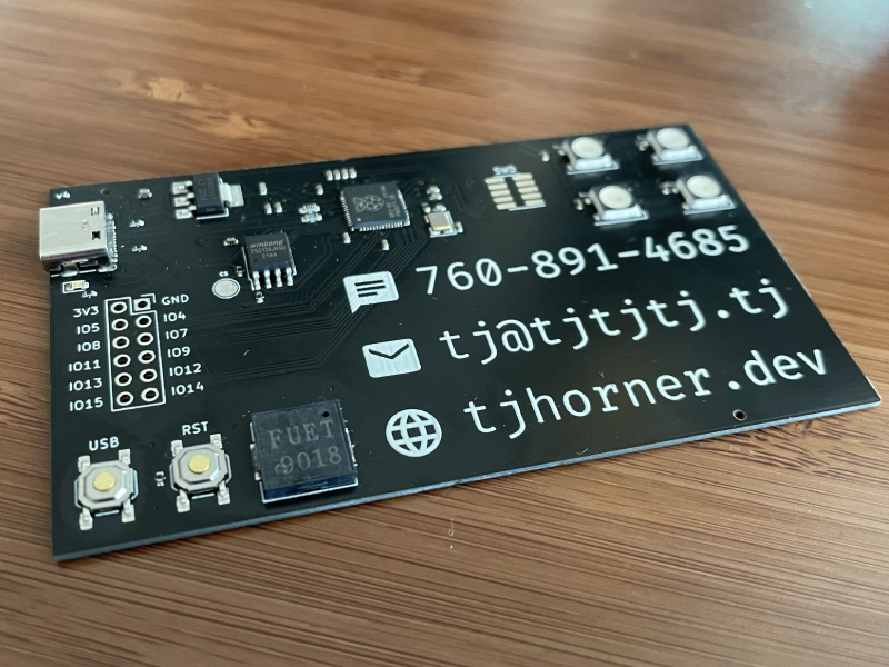 A photo of my PCB business card in the flesh. It has my contact details and several peripherals attached.